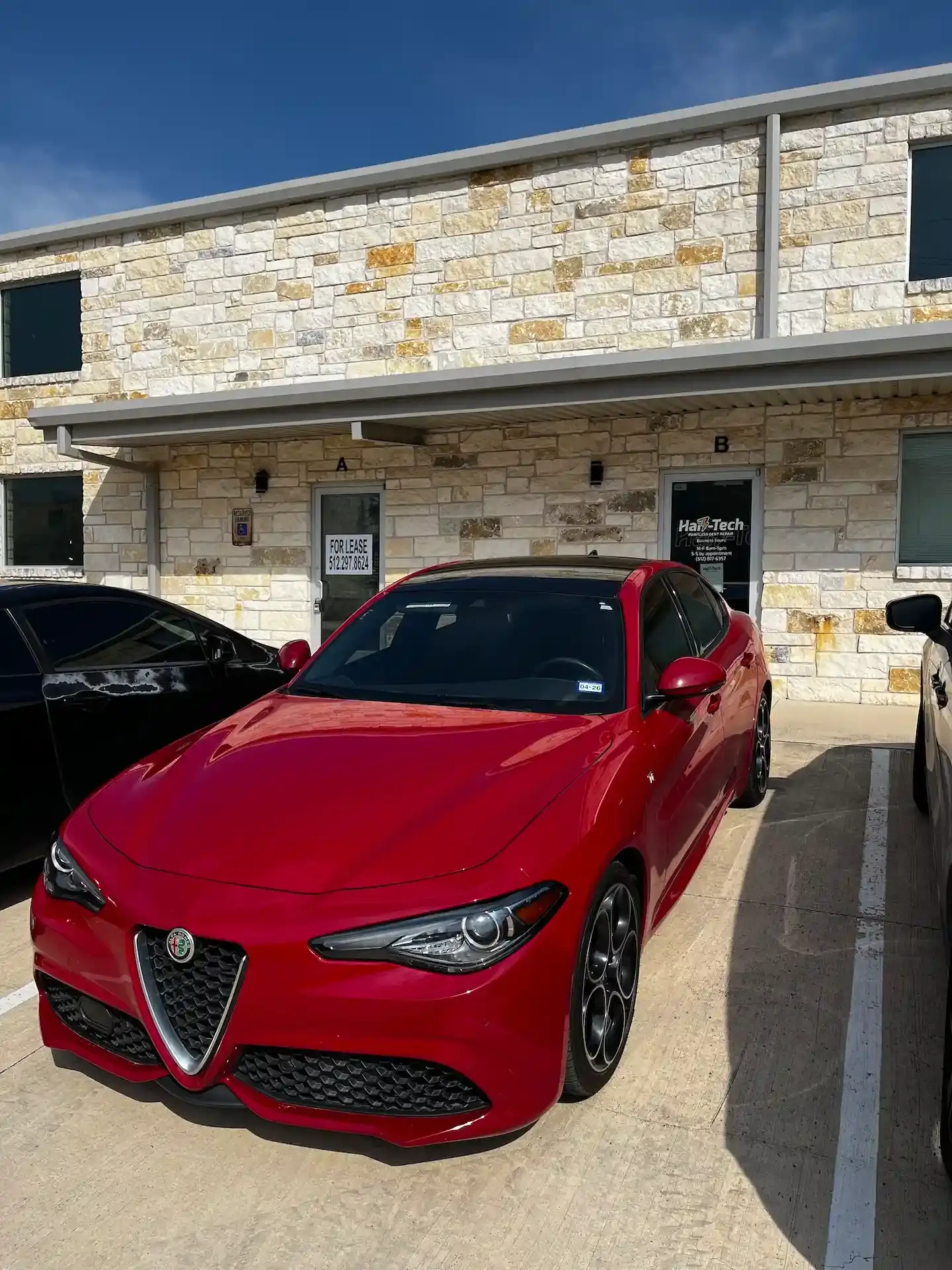 Red Alfa Romero parked outside of Hail-Tech PDR dent repair studio on Anderson Mill.