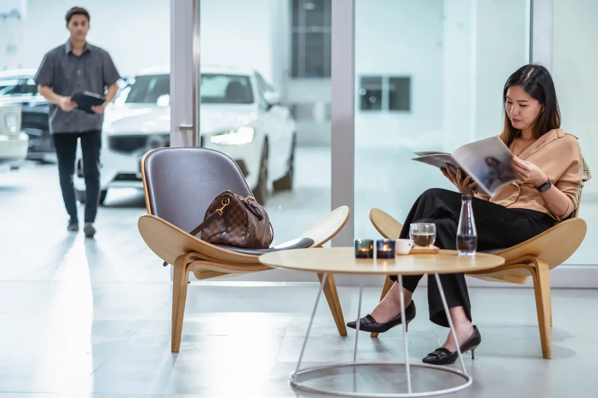 A woman waits while her car is being worked on at a garage.