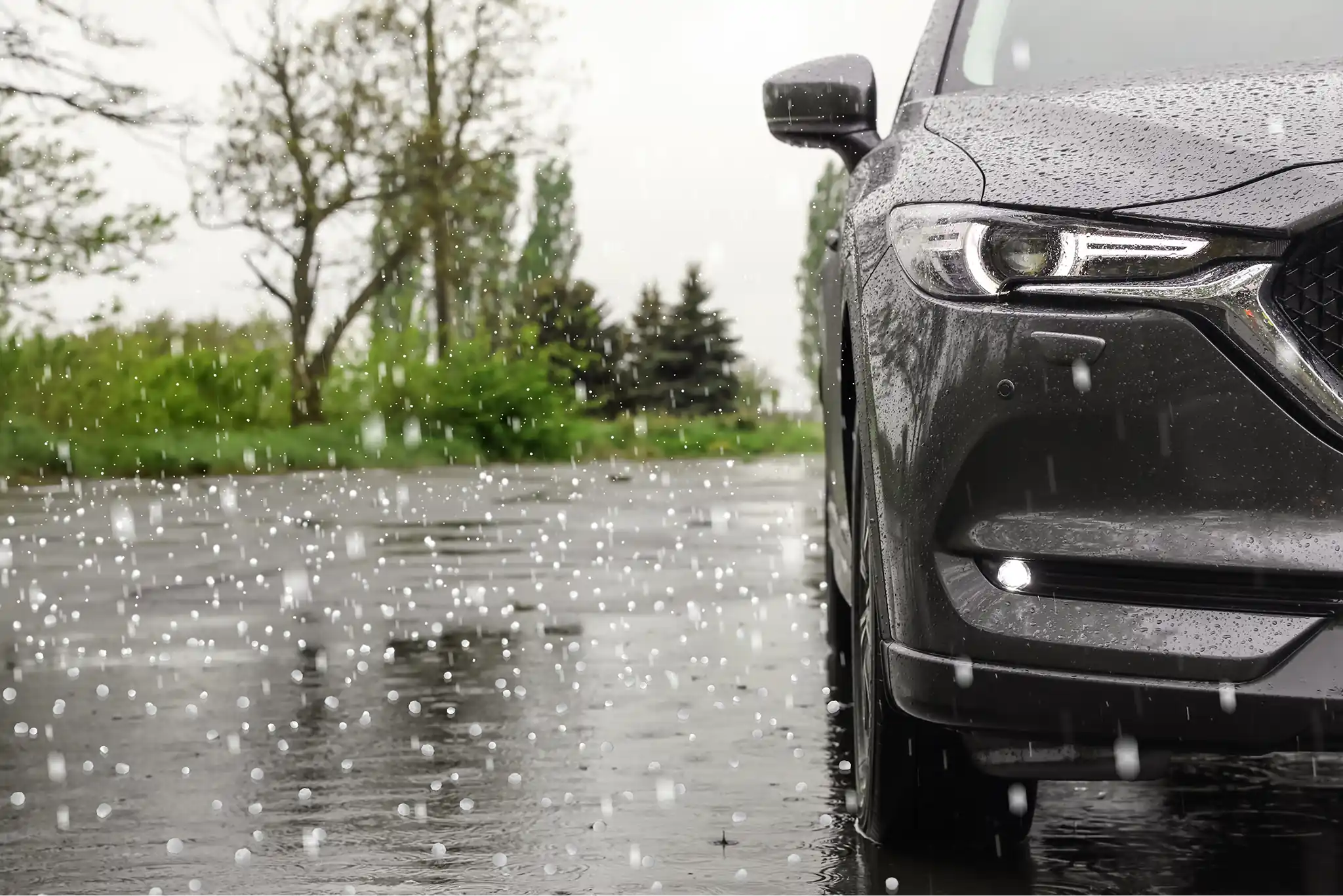 Gray SUV parked outdoors during a heavy rain and hailstorm