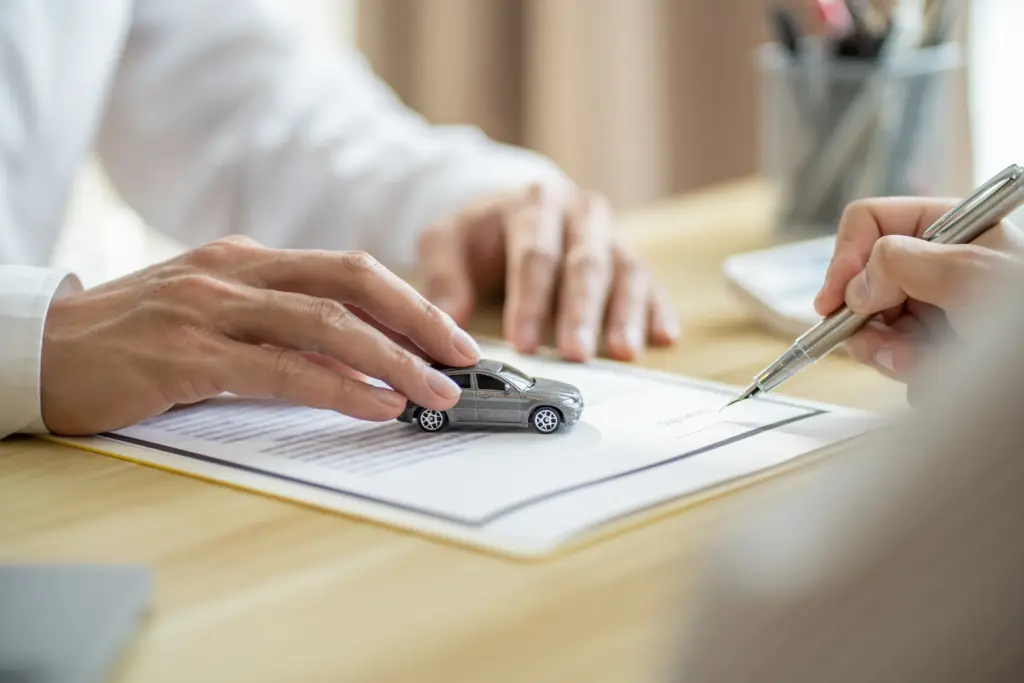 How to Choose a PDR Shop: What to Look For and What to Walk Away From 2 Person signing a vehicle repair or insurance document at a desk